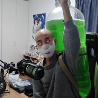 男性,マスク,大きなペットボトル,緑色の液体,室内,パソコン,マイク,フィギュア,ポスター